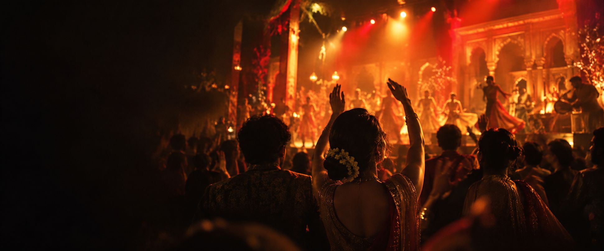 Audience with raised hands in front of a lit festival stage
